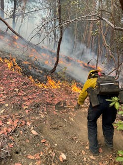 A firefighter is &ldquo;going direct&rdquo; in the attack of a wildfire by constructing a hand line.