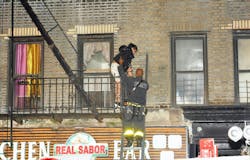 An FDNY firefighter rescues a resident at the March 20 fire where three children were left at home alone.