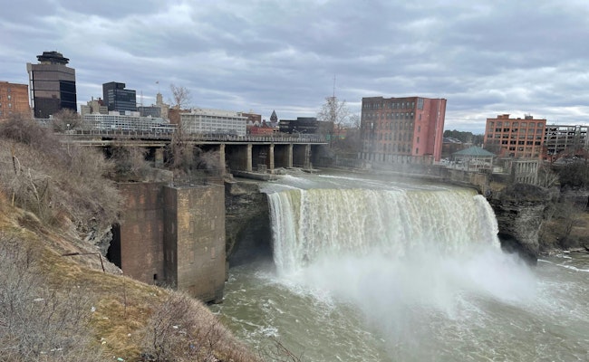 The brick building that’s on the far side of High Falls, which is located in downtown Rochester, NY, was the scene of a recovery of a victim who fell into a 20 x 20-foot void shaft. Rail traffic on the railroad trestle that’s above the waterfall played a part in the difficult job.