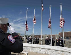 Honor Guard members salute as flags are flown over the National Fallen Firefighters Memorial.