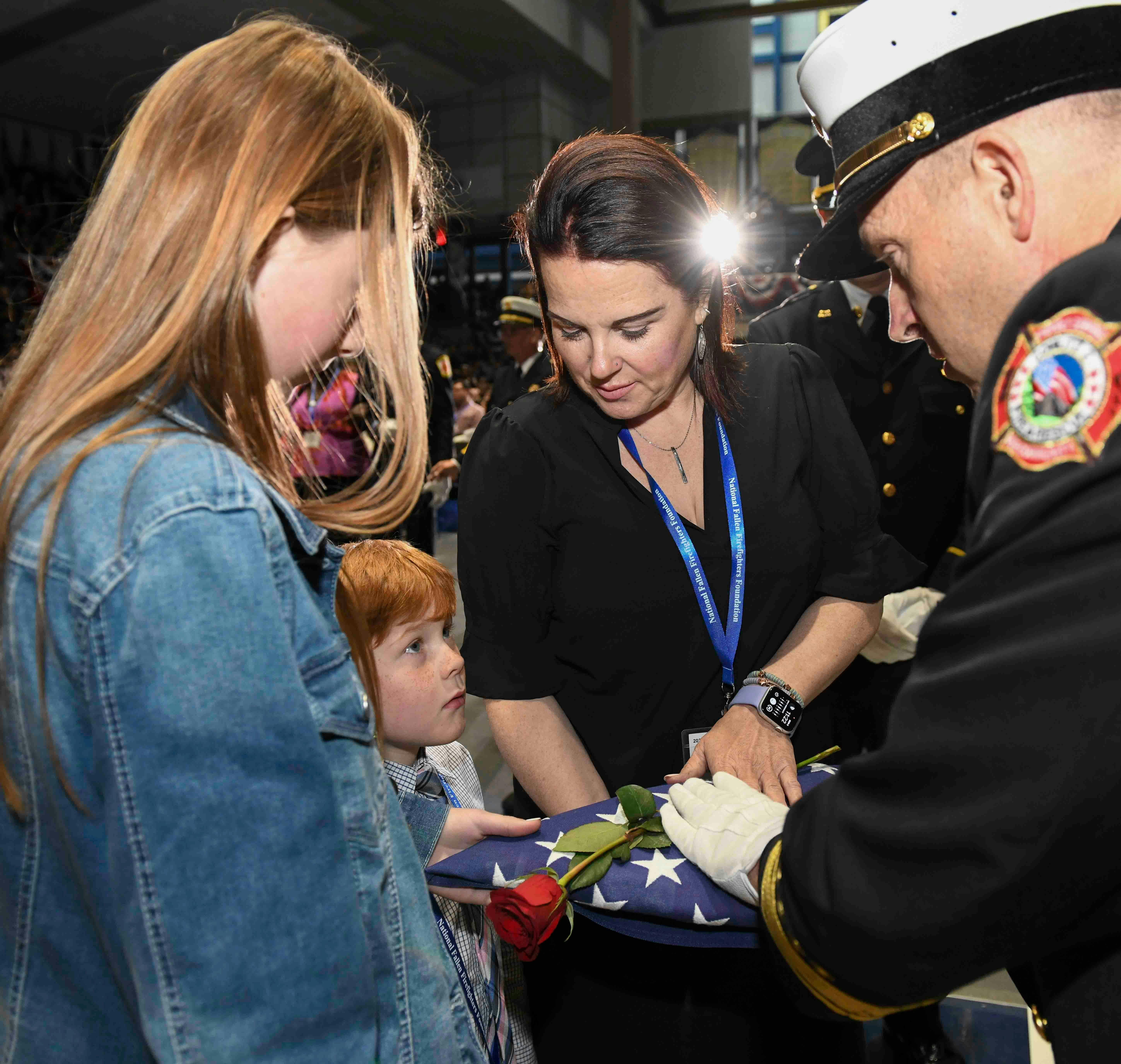 A child listens intently to the words of a fire official while receiving a flag during the National Fallen Firefighters Memorial Service.