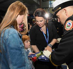 A child listens intently to the words of a fire official while receiving a flag during the National Fallen Firefighters Memorial Service.
