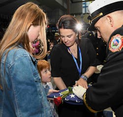 A child listens intently to the words of a fire official while receiving a flag during the National Fallen Firefighters Memorial Service. A child listens intently to the words of a fire official while receiving a flag during the National Fallen Firefighters Memorial Service.