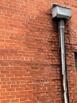 Load-bearing brick walls have a header or bond course of bricks laid, by which the ends are visible in every fifth or seventh row of brick. Load-bearing brick walls will be several layers of brick thicker than a veneer wall. Weather damage to the wall is evident from a leaking roof drain.