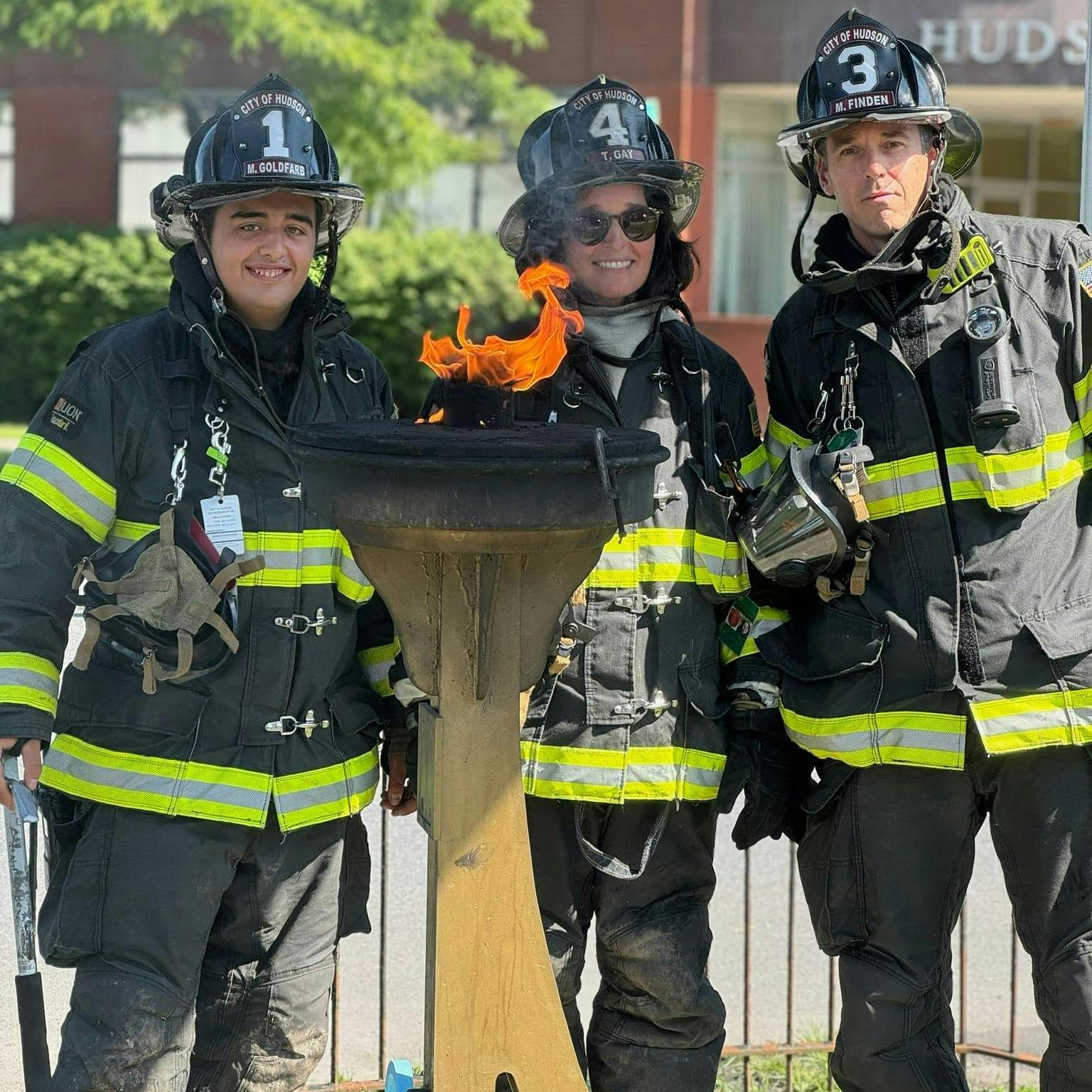 Firefighters from the City of Hudson pose with the Olympic torch that ignited Sunday morning after the cover was dislodged, just hours before the 2024 Olympic Games came to an end.