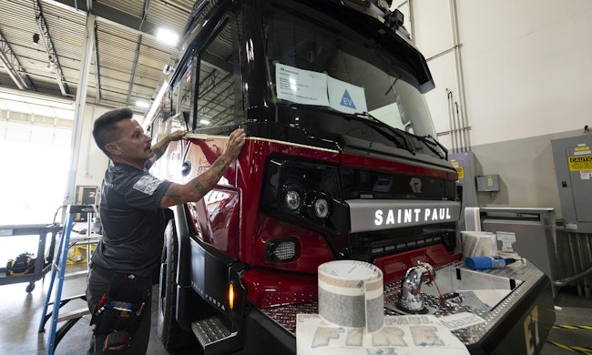 Adam Brinkman, with Grafix Shoppe, applies trim decals on to a Rosenbauer RTX fire engine.