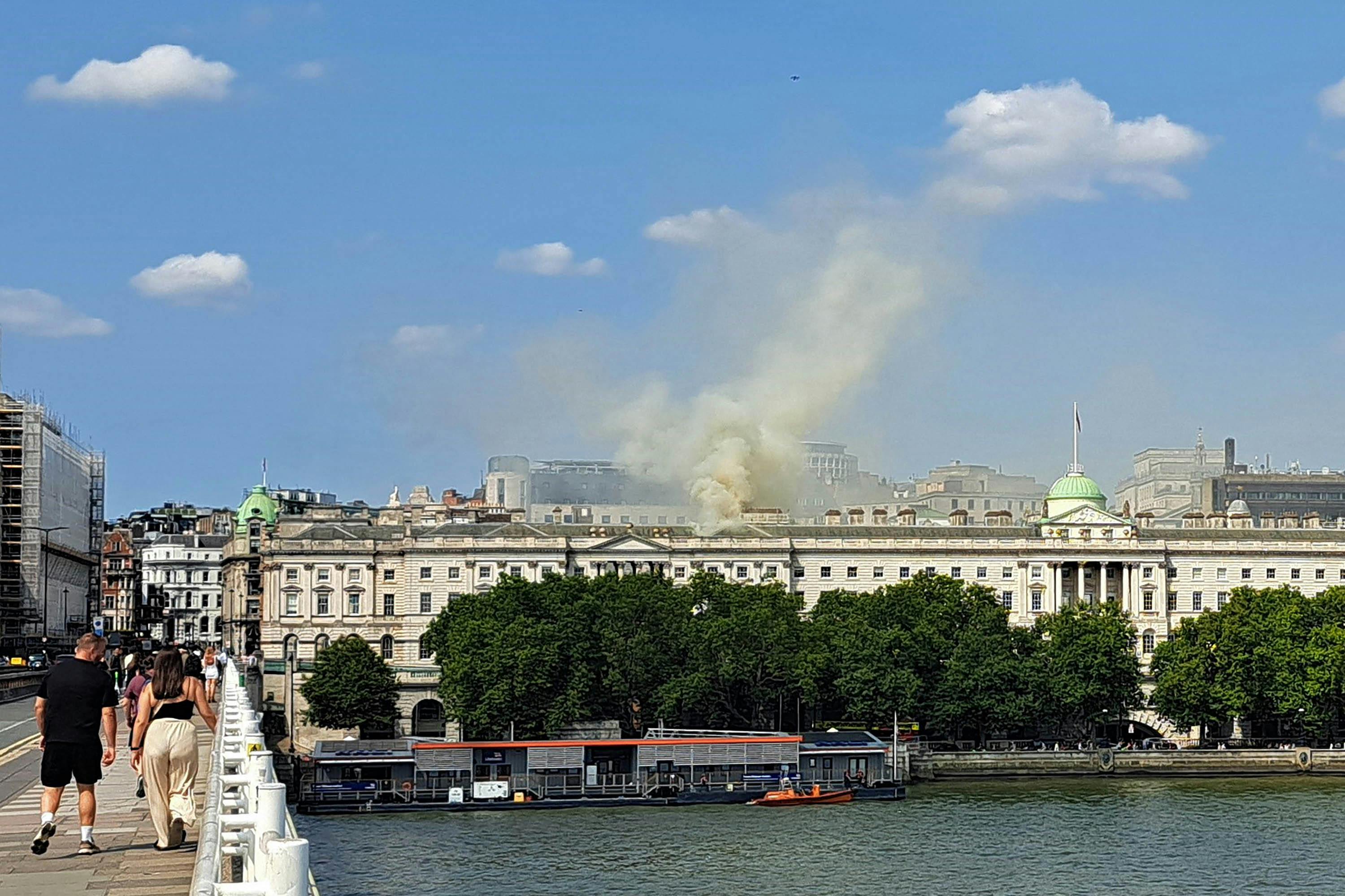 Smoke billows from the roof of Somerset House, beside the River Thames, in London on Saturday.