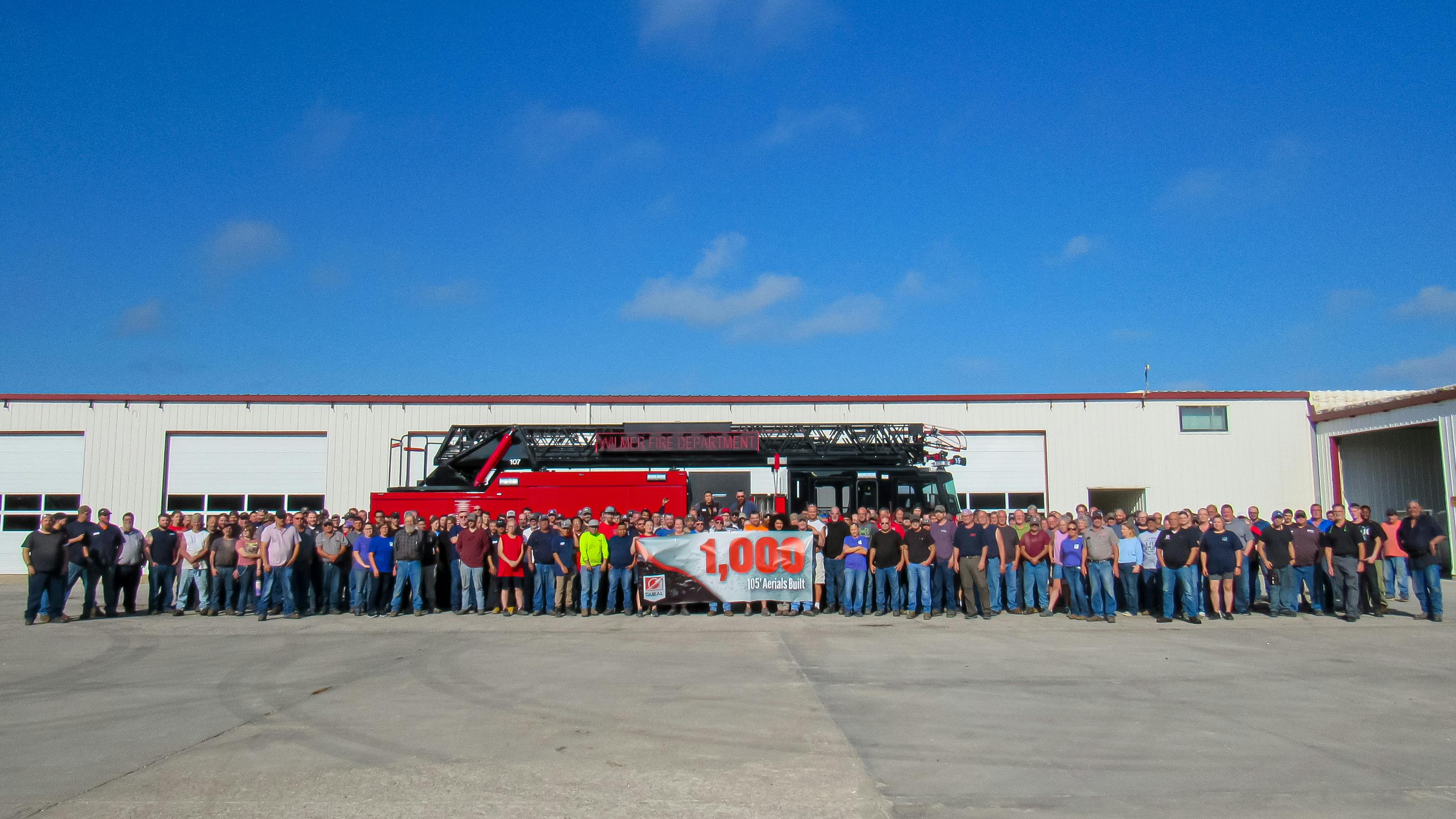 Workers pose with the 1,000th 105-foot Smeal aerial apparatus that was completed at their Snyder, NE, facility. The aerial ladder was built for the Wilmer, TX, Fire Department.