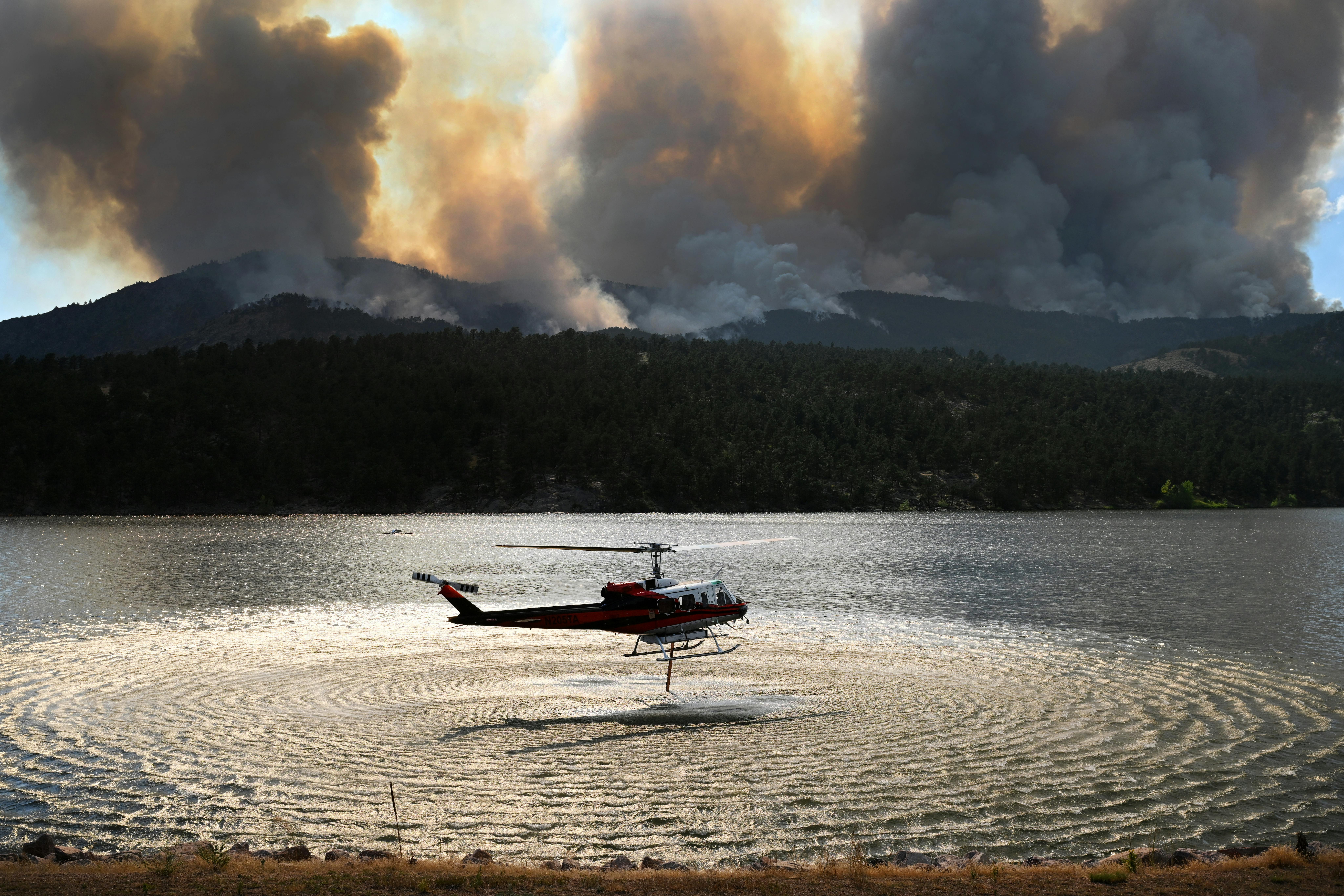 A helicopter fills up to drop water on the Alexander Mountain fire burning west of Loveland on Monday, July 29, 2024.