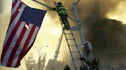 FDNY Capt. Michael Dugan hangs a flag from a light pole in front of what is left of the World Trade Center after it was destroyed in a terrorist attack.