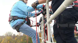 Firefighter Paul Semaan helps Michigan House of Representatives Denise Mentzer over the edge to rappel down the live burn tower at Macomb Community Colleges Public Service Institute.