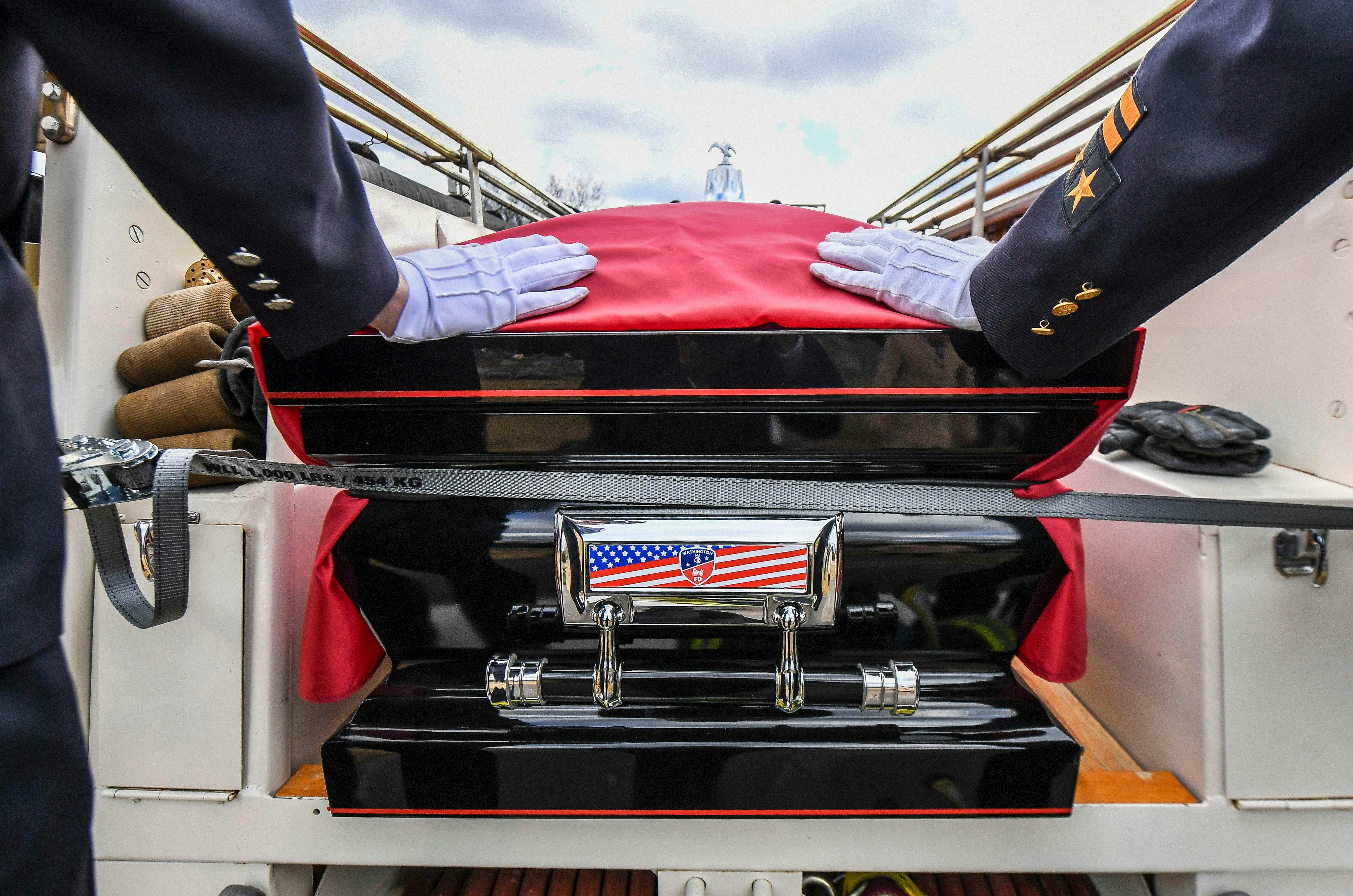 Firefighters guide the casket of longtime Washington Fire Chief Charles Wright into the hose bed of an antique rig.