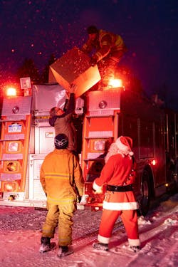 Charlotte, MI, firefighters helping Santa get gifts down from the fire engine. Charlotte, MI, firefighters helping Santa get gifts down from the fire engine.