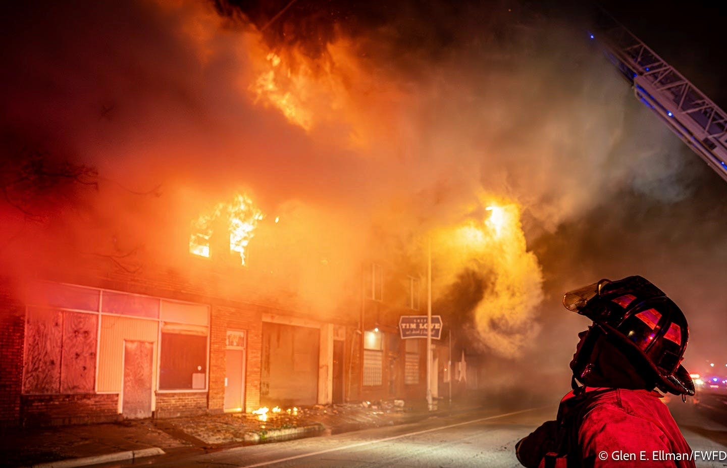 A Fort Worth firefighter surveys the scene as flames engulf a vacant warehouse.