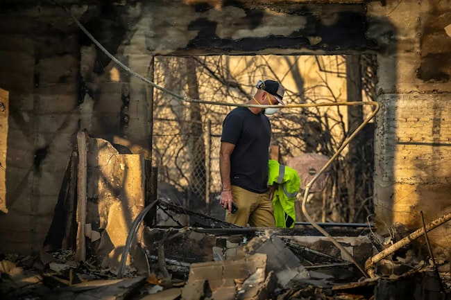 George Cunningham walks through the rubble of his house in Altadena, which was destroyed in the Eaton fire. Firefighters and others are beginning to search the rubble for victims who did not make it out in time.