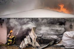 A Fort Worth firefighter operates a hoseline in the garage as fire shoots from the roof of the home. A Fort Worth firefighter operates a hoseline in the garage as fire shoots from the roof of the home.