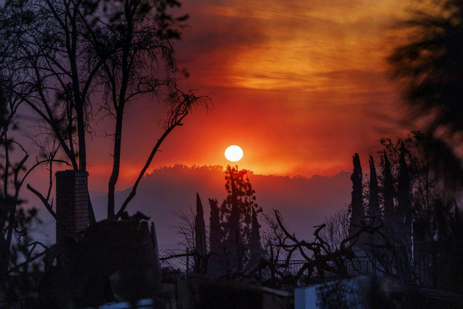 A smoky haze fills the dusk landscape as a home smolders in the foreground during the Eaton fire in Altadena on Jan. 8.