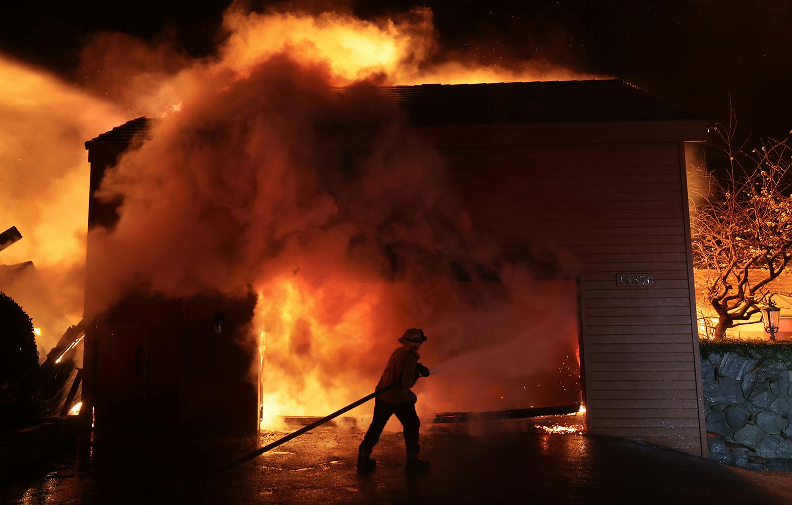 A firefighter battles a house fire during the Palisades Fire on Jan. 8, 2025.