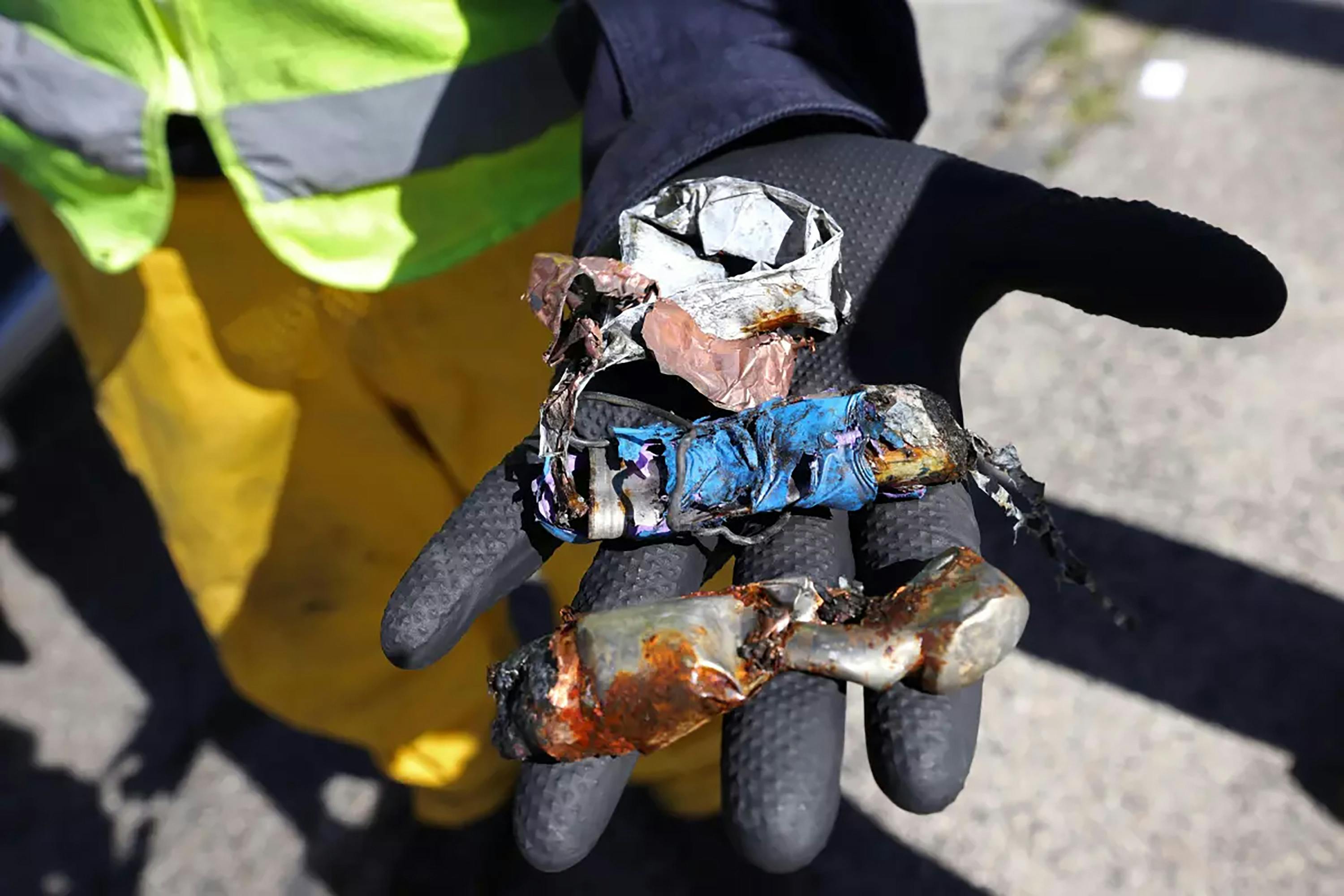 A worker shows lithium-ion batteries after they were shredded.
