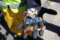 A worker shows lithium-ion batteries after they were shredded. A worker shows lithium-ion batteries after they were shredded.