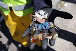 A worker shows lithium-ion batteries after they were shredded. A worker shows lithium-ion batteries after they were shredded.