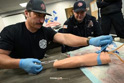 Denver Firefighter Bill Coghill, left, practices placing an IV into a fake arm while hazmat technician Collyn Mashek, right, watches. Denver Firefighter Bill Coghill, left, practices placing an IV into a fake arm while hazmat technician Collyn Mashek, right, watches.