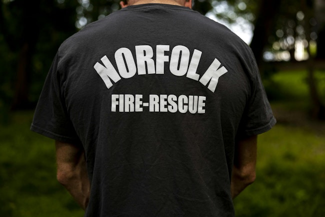 Former Norfolk firefighter Brandon Beltaine wears a Norfolk Fire-Rescue T-shirt while standing for a portrait after he was fired in 2023 for medical marijuana use off the job.
