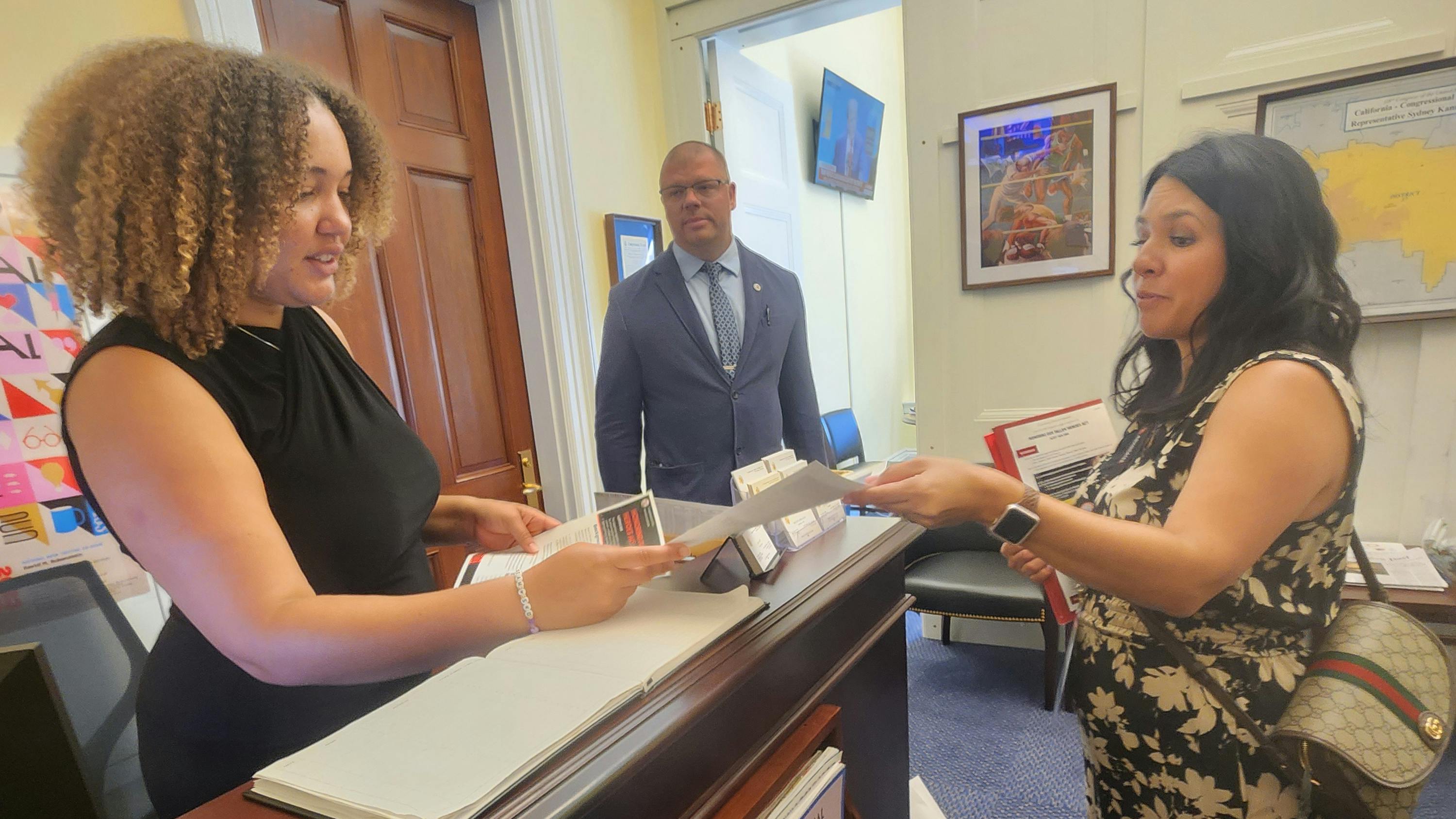 Cylina Cervantes, right, hands a legislative staff member while Westfield Firefighter Josh Southerland listens.