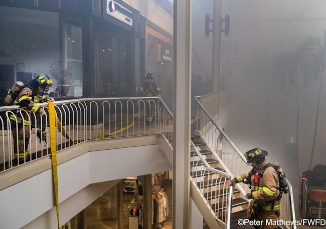 Firefighters stretch a hoseline to the second-story of Hulen Mall for fire attack.