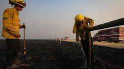 Monterey County firefighters Jonathan Davis, left, and Ryan Cahalan extinguish smoldering wood posts on a cattle fence after the Madre Fire burned through the area on July 3.