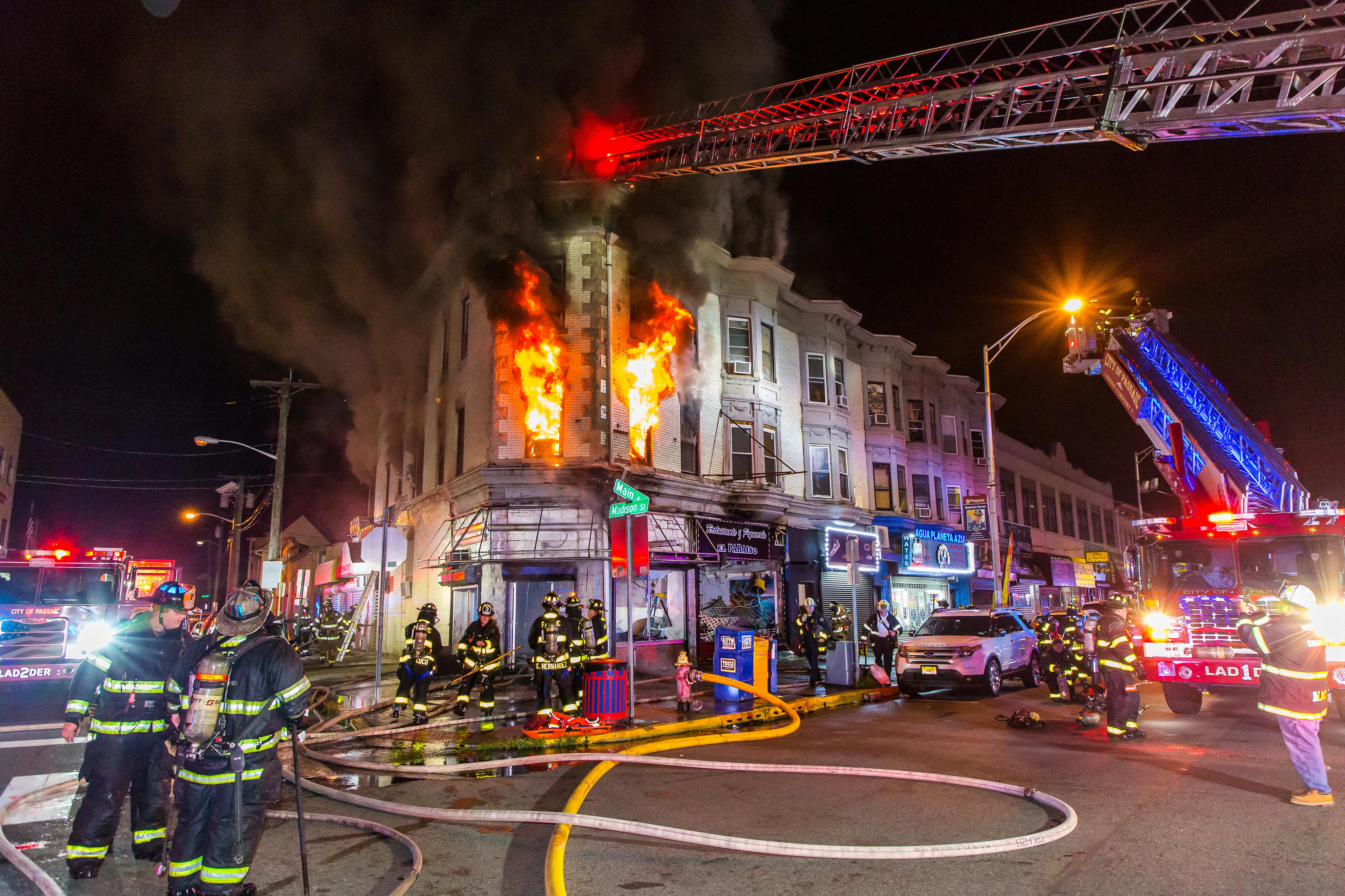 First-arriving Passaic Fire Department crews reported heavy smoke showing from first-floor stores and upper-floor apartments of a three-story mixed occupancy. Heavy fire in one store prompted a second alarm. During search operations, Ladder 1 reported heavy fire in the ceiling. A third alarm was transmitted, which brought mutual aid from Bergen and Essex counties. With four lines operating, crews removed several occupants. With heavy fire visible on the second floor and thick, black smoke pushing from the second and third floors, command ordered all companies out and transitioned to a defensive attack.