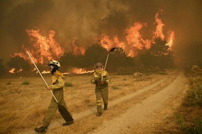 Residents try to battle one of nearly two dozen wildfires in burning across Spain this week. One fire, near Leon, claimed the lives of two volunteer firefighters.