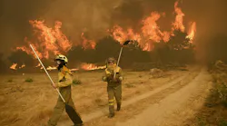 Residents try to battle one of nearly two dozen wildfires in burning across Spain this week. One fire, near Leon, claimed the lives of two volunteer firefighters.