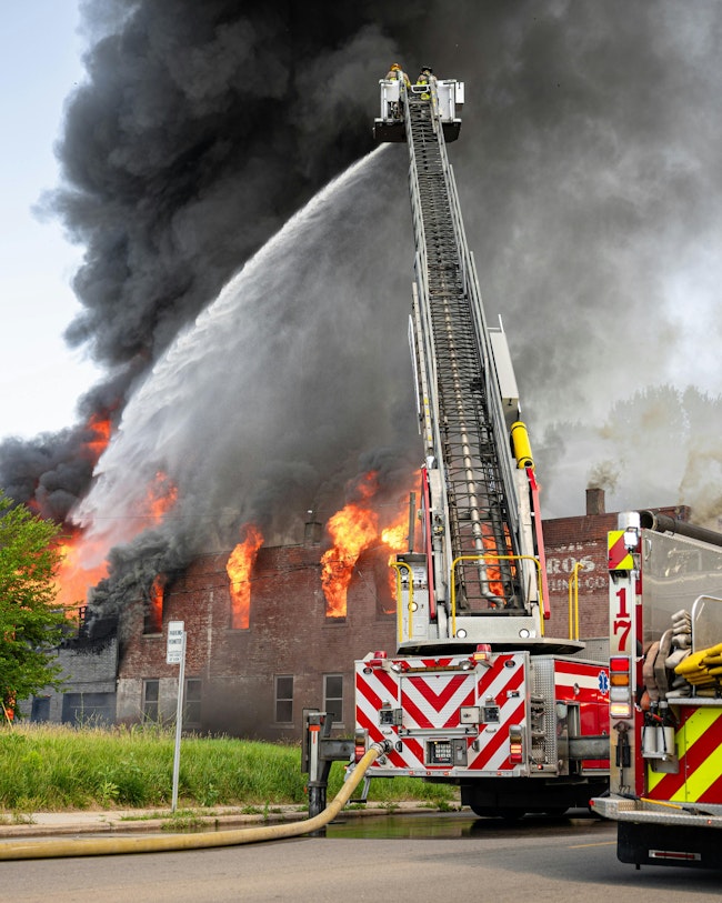 The Toledo Fire and Rescue Department responded to a commercial building fire. Crews arrived to find heavy fire showing and were forced to fight the fire defensively. Two ladder trucks used their elevated master streams, and members operated multiple handlines to bring the blaze under control. Firefighters operated on scene for more than eight hours. They faced numerous challenges, including multiple exposures, downed power lines, and high air temperatures and humidity.