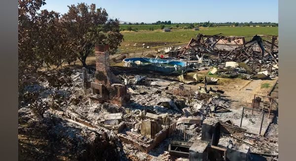 A chimney stands amid the rubble of a structure at a fireworks explosion site.
