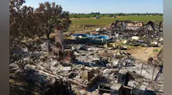 A chimney stands amid the rubble of a structure at a fireworks explosion site.