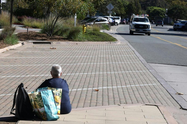 A homeless woman sits in a park in Malibu, CA.
