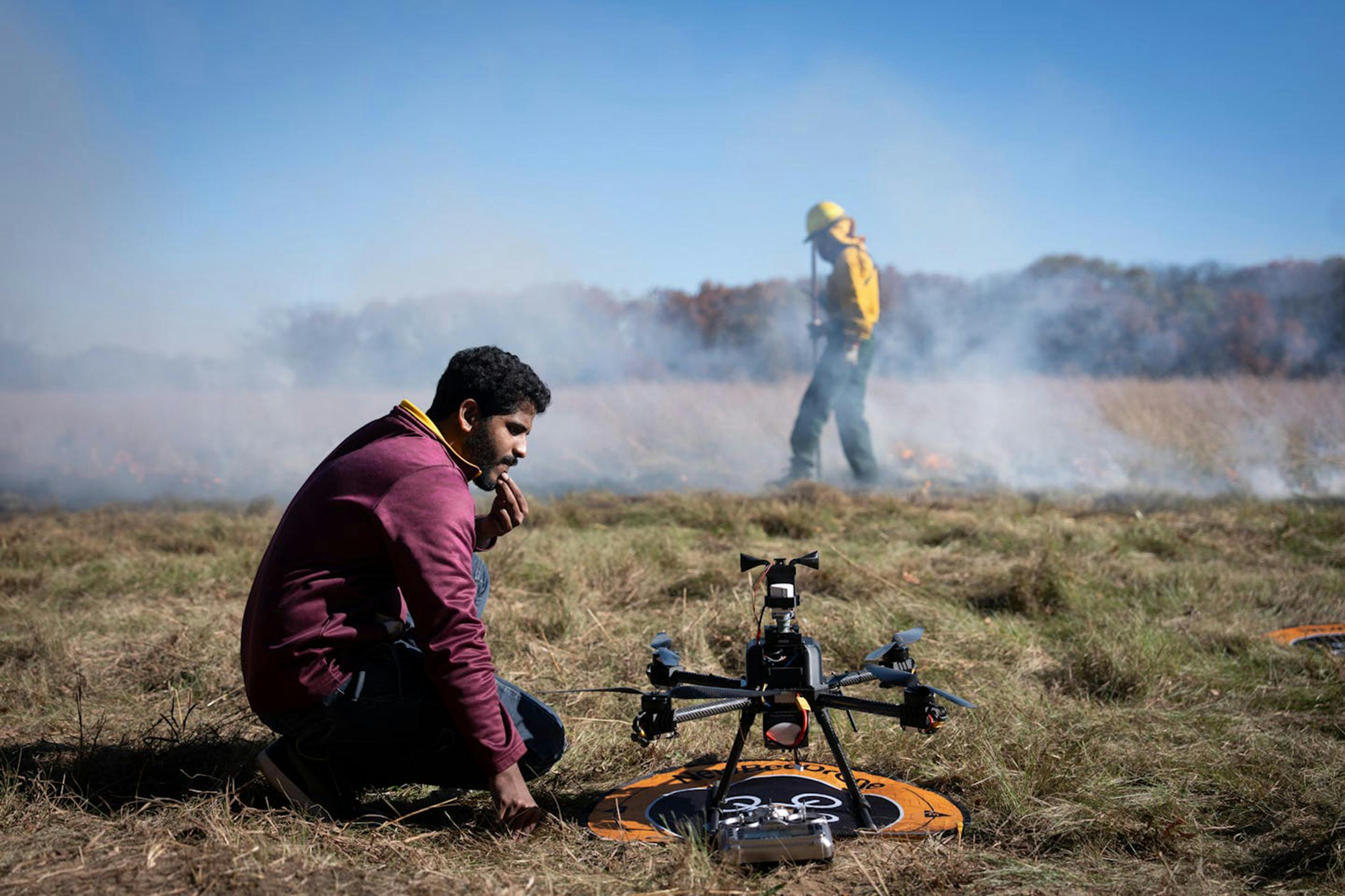 University of Minnesota researcher Nikil Krishnakumar prepares a drone to fly through smoke while Department of Natural Resources staff light a backfire in East Bethel, MN, last month.