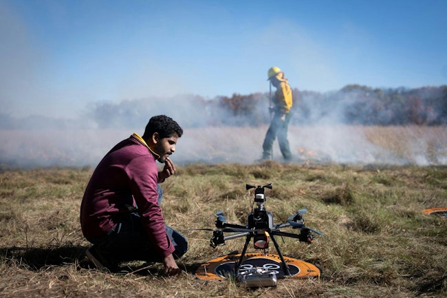University of Minnesota researcher Nikil Krishnakumar prepares a drone to fly through smoke while Department of Natural Resources staff light a backfire in East Bethel, MN, last month.