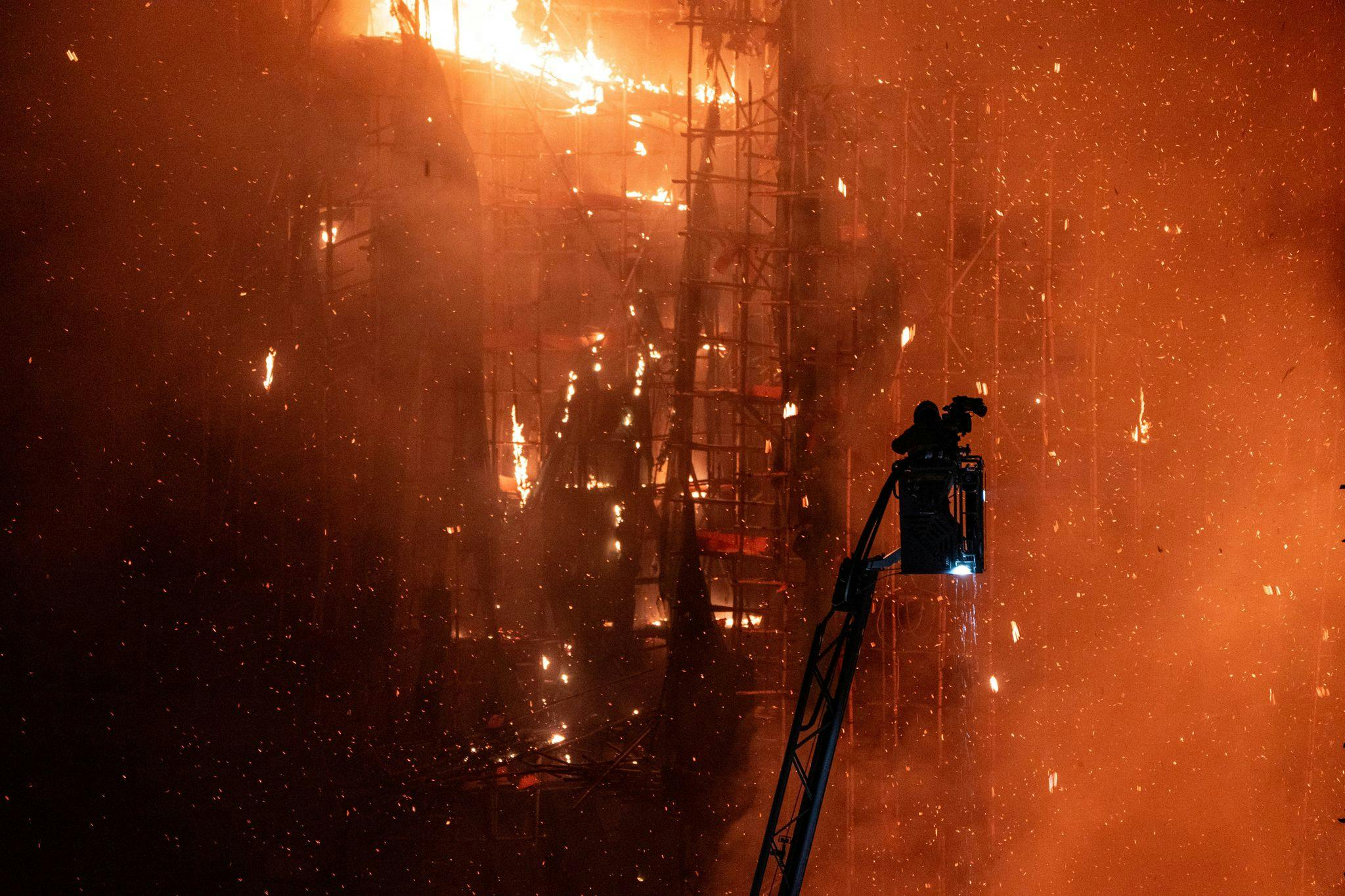 A firefighters prepares to put water on flames as they engulf a burning high-rise building in Hong Kong.