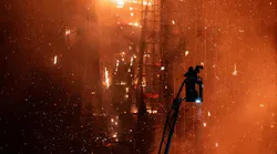 A firefighters prepares to put water on flames as they engulf a burning high-rise building in Hong Kong.