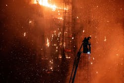 A firefighters prepares to put water on flames as they engulf a burning high-rise building in Hong Kong. A firefighters prepares to put water on flames as they engulf a burning high-rise building in Hong Kong.