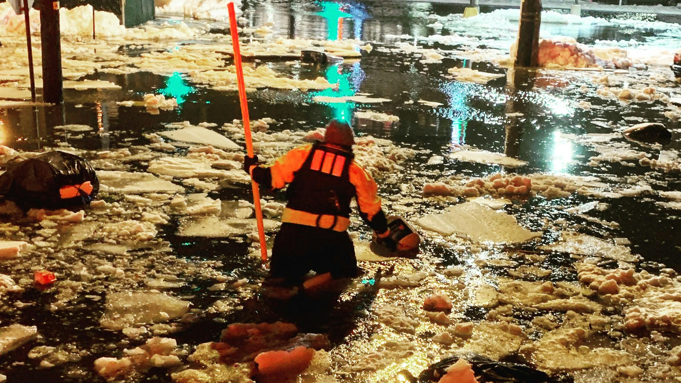 A flood-rescue technician removes a hazard from the roadway during nor&rsquo;easter flooding.