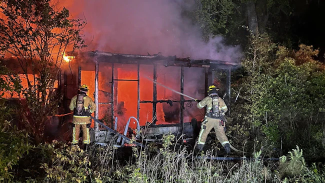 The Burton Fire District battles a fire in an abandoned structure without power where homeless people were reported to have been staying.