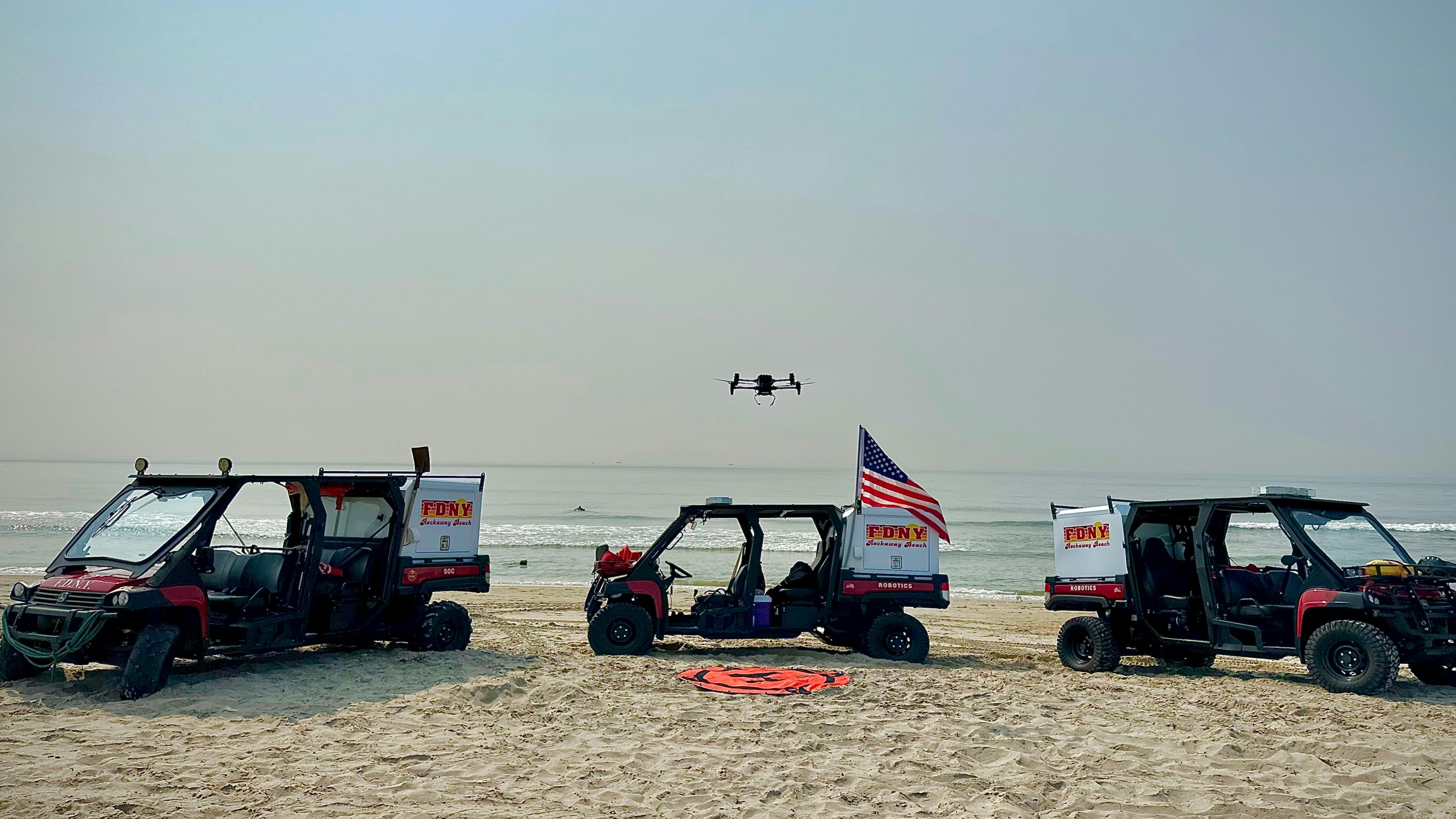 FDNY is among early technology adopters by understanding where technology can help mitigate incidents. Here, a drone hovers among FDNY vehicles that are used in a collaborate effort to prevent drownings at beach in the Borough of Queens.