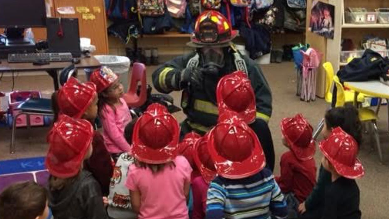 firefighter in full gear during fire safety lesson with young children