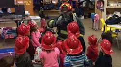 firefighter in full gear during fire safety lesson with young children
