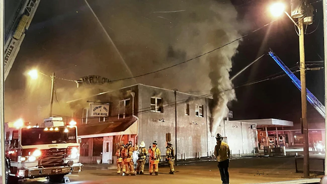 firefighters and aerial ladder truck on scene of restaurant fire