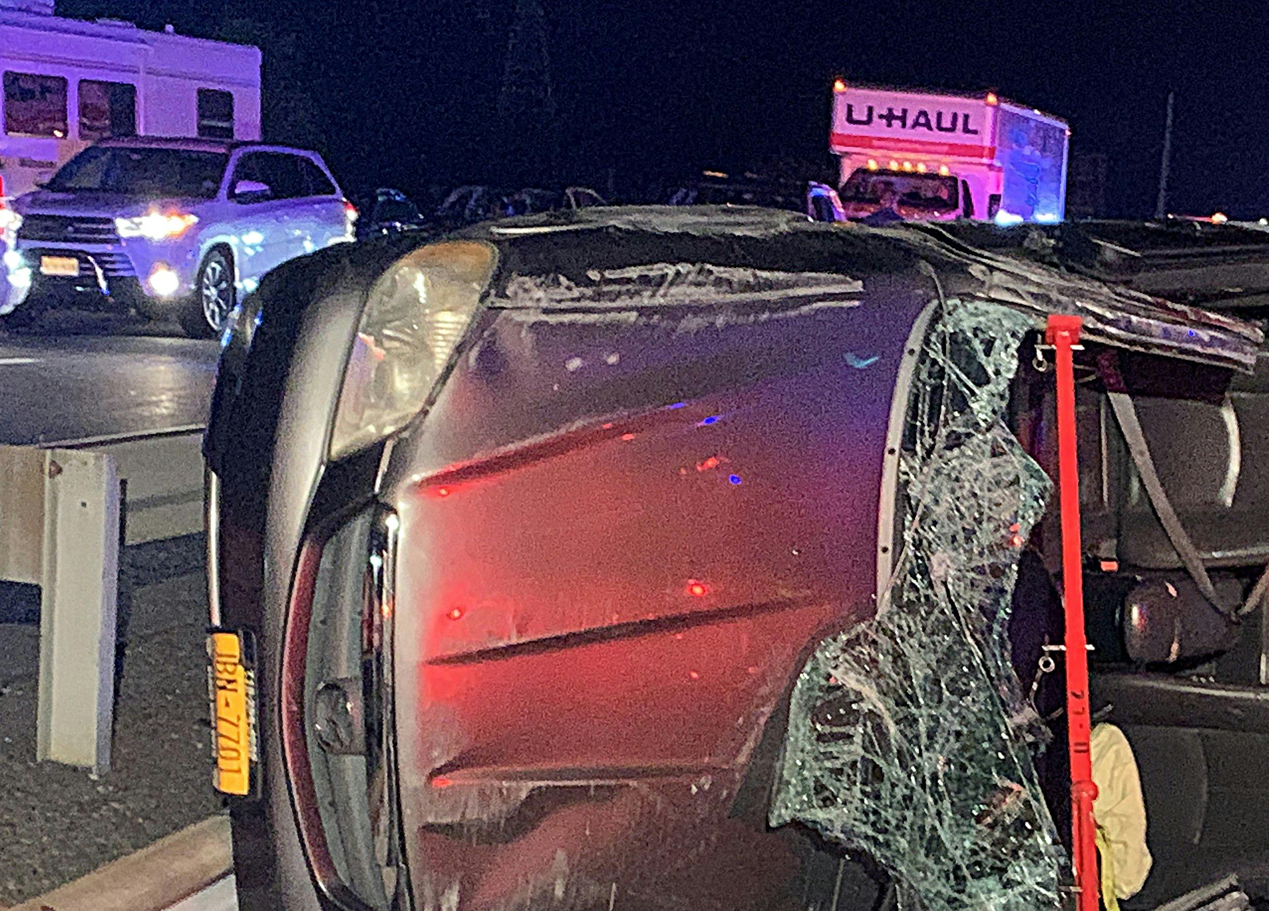 crashed automobile on its side amid moving traffic