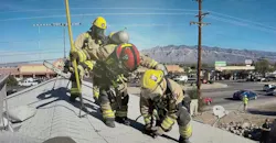 firefighters on a roof deploying a piercing nozzle to put water on an attic fire that's below them